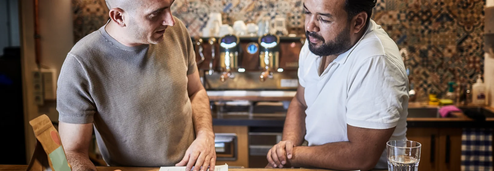Two roasters discuss prices in a coffee shop.
