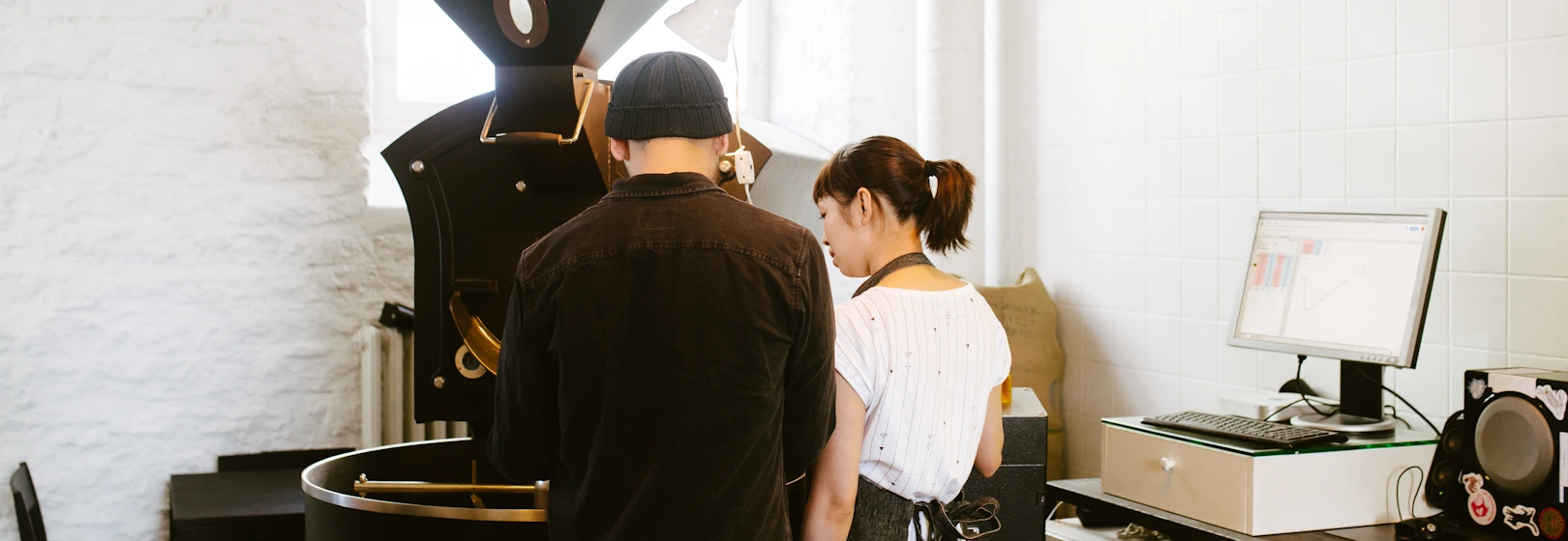 Two roasters inspect coffee on a machine.